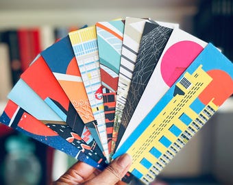 May include: A collection of colorful bookmarks featuring geometric designs and illustrations of buildings. The bookmarks are arranged in a fan shape and labeled "The Brutalist Collection".