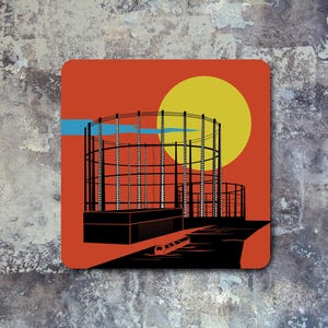 May include: An illustration of a large gas holder with a canal in the foreground. The gas holder is a large, cylindrical structure with a series of horizontal rings. The canal is a narrow waterway with a small boat in it.