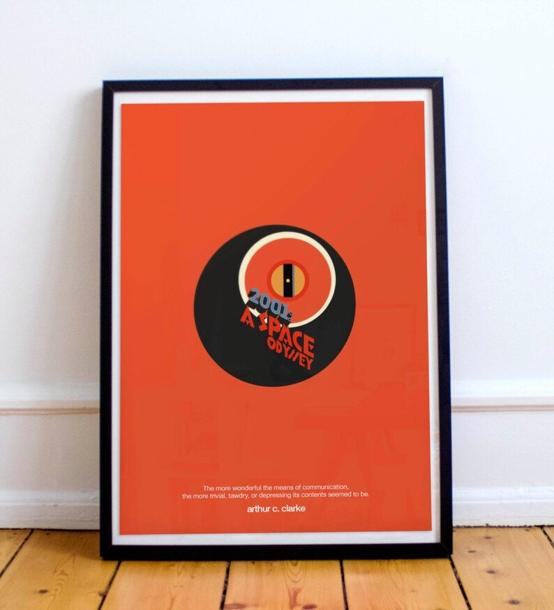 May include: A minimalist poster with a red background featuring a black and white circle with the text "2001 A SPACE ODYSSEY" in white. The quote "The more wonderful the means of communication, the more trivial, tawdry, or depressing its contents seemed to be. - arthur c. clarke" is printed in white at the bottom.