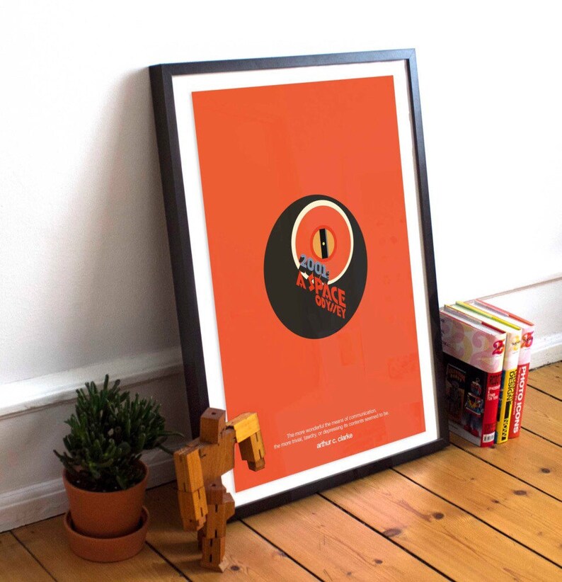 May include: A framed poster with a minimalist design featuring a black circle with a red eye and the text "2001 A SPACE ODYSSEY". The poster has an orange background and a quote by Arthur C. Clarke at the bottom.