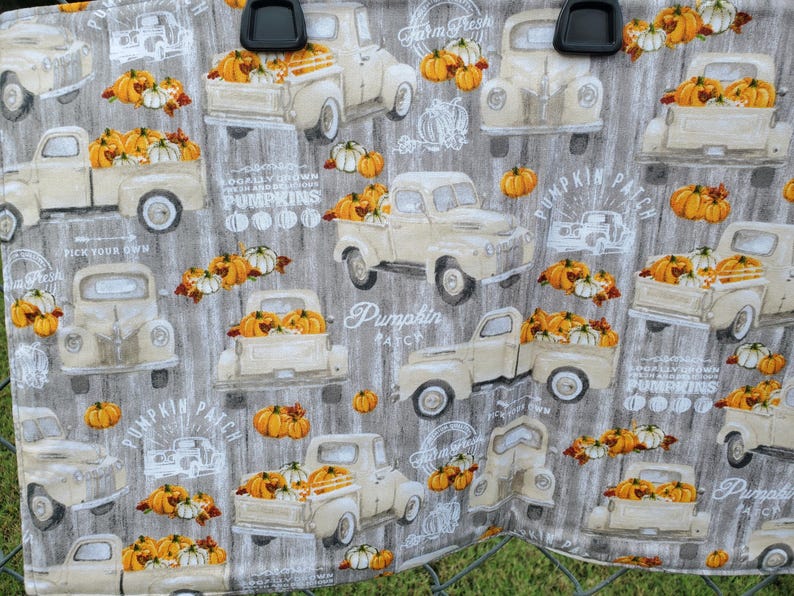 May include: Fabric with a repeating pattern of vintage cream-colored trucks filled with pumpkins and white gourds. The background is a gray wood grain design. Text includes "Farm Fresh", "Pumpkin Patch", and "Pick Your Own".
