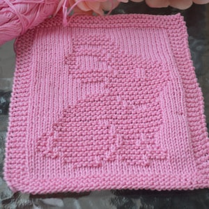 Może przedstawiać: Różowa dziana ściereczka do naczyń z geometrycznym wzorem. Ściereczka jest wykonana z miękkiej, chłonnej przędzy.