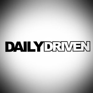 May include: A graphic featuring the text "DAILY DRIVEN". The word "DAILY" is in solid black, and "DRIVEN" is outlined in black with a white fill. The background is a gradient from white to grey, creating a subtle effect.