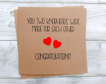 May include: A brown card with the text "You two knobheads were made for each other. Congratulations!" with two red hearts.