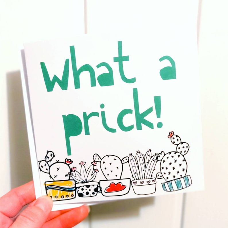 May include: A white card with the text "what a prick!" in green letters. The bottom of the card features a row of black and white cactus illustrations in pots.