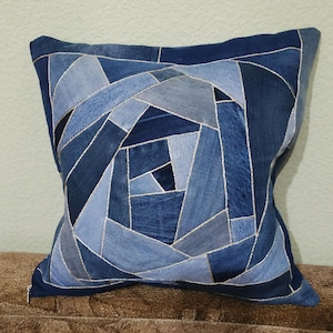 Könnte beinhalten: Ein blauer Jeans-Kissenbezug mit einem geometrischen Muster aus verschiedenen Blautönen von Jeans. Der Kissenbezug ist mit silbernem Garn zusammengenäht.