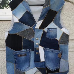 Puede incluir: Un chaleco sin mangas confeccionado con un mosaico de diversas telas de mezclilla en tonos azul, negro y blanco. La prenda cuenta con cuatro botones metálicos, dos bolsillos inferiores y un bolsillo en el pecho, cada uno con la marca DISSEL.