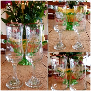 May include: Four clear glass champagne flutes with red rims. Each flute has a white design with the text "On Your Ruby Anniversary".