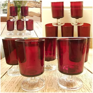 Puede incluir: Conjunto de ocho vasos de vidrio rojo con tallo. Los vasos son transparentes con un tinte rojo y tienen un tallo corto.