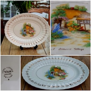 May include: A white oval serving platter with a gold rim and a floral design featuring a cottage. The platter is made by Wade England Pottery and has the words "A Somerset Cottage" printed on it.