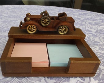 May include: Wooden desk organizer with a vintage car figurine on top. The organizer has two compartments for sticky notes, one pink and one blue.