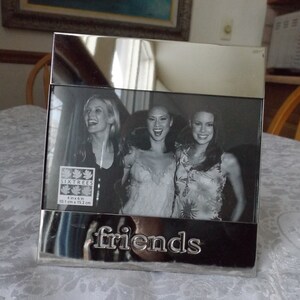 May include: Silver picture frame with a black and white photo of three women. The frame has the word "friends" engraved on the bottom. The photo is 4x6 inches (10.1 cm x 15.2 cm).