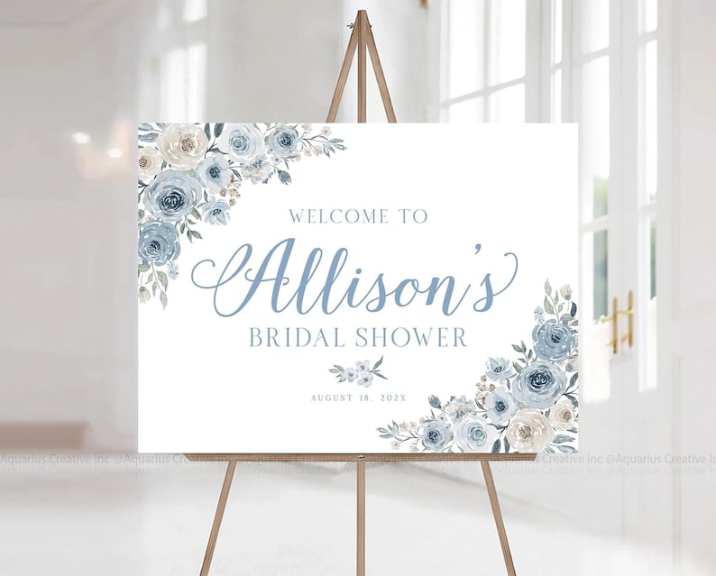 Op de afbeelding: Een wit welkomsbord met blauwe en cr&egrave;mekleurige bloemenontwerpen. Het bord luidt "Welkom bij Allison's Bridal Shower August 18, 202X".