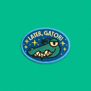 May include: A blue and yellow embroidered patch with a cartoon alligator and the text "Later, Gator!"