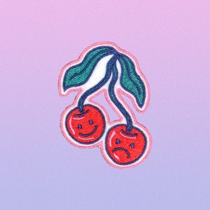 May include: Two embroidered cherries with happy and sad faces, on a pink and purple gradient background.