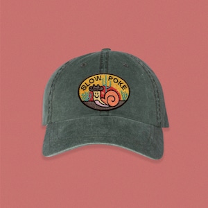 May include: A dark green, vintage-style baseball cap with an embroidered patch featuring a cartoon snail wearing a cowboy hat and the text "Slow Poke".