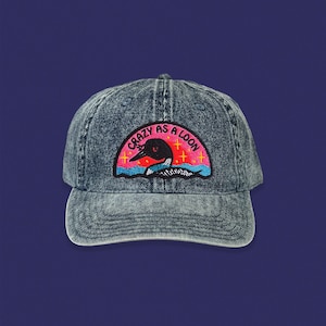 May include: A blue denim baseball cap with an embroidered patch that says "Crazy as a Loon" and features a loon in a pink and red sunset.