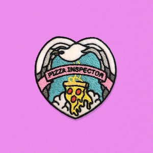 May include: An iron-on patch in the shape of a heart featuring a seagull holding a slice of pizza. The seagull is white with black eyes and beak. The pizza is yellow with red pepperoni and a white crust. The banner reads "Pizza Inspector".