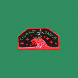 May include: Black and red embroidered patch with a skeleton surfing a wave. The text "CWB HOT SAUCE" is written in white on the patch.