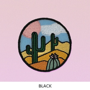 May include: A round embroidered patch with a desert scene. The patch features two green cacti, a pink and blue sky, and yellow sand dunes. The patch is outlined in black.