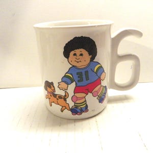 1985 Cabbage Patch Kids Growing Up Ceramic Mug #6 , 1980's CPK Cup - Rollerskating Boy with Puppy Number 6