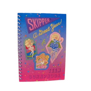 May include: A vintage spiral-bound scrapbook with a blue, pink, and purple cover. The cover features the word "SKIPPER" in pink and the phrase "A Great Year!" in yellow. Illustrations of a blonde girl are on the cover. The words "TEEN SCRAPBOOK" are at the bottom.