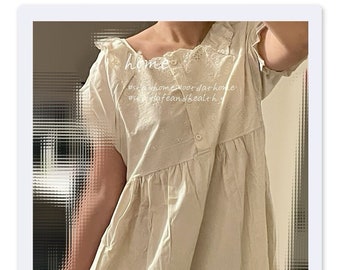 May include: A white cotton dress with a lace trim and a button closure. The dress has a loose fit and falls to the knees. The text "#stayhome #forthathome #safeandhealthy" is printed on the dress.