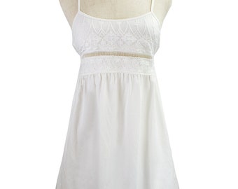 May include: A white sleeveless dress with a lace bodice and a gathered skirt. The dress is on a mannequin.