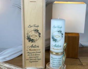 May include: A wooden box with a rope handle and a white candle with a green and gold floral design. The box and candle are decorated with the text "Zur Taufe" and the name "Anton". The text on the candle reads "Moge jeder Schritt den du in deinem Leben machst von Liebe und Segen begleitet sein".