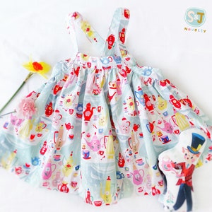 May include: A light blue sleeveless dress with a teacup and teapot pattern. The dress has adjustable straps and a gathered skirt. The dress is paired with a small toy doll wearing a top hat and a red vest.