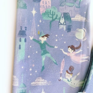 May include: Purple fabric with a repeating pattern of a night sky with stars, clouds, buildings, and characters from Peter Pan. The characters include Peter Pan, Wendy, and Captain Hook.