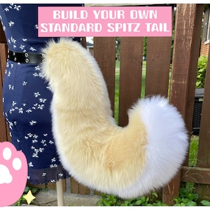 Puede incluir: Una cola de spitz de piel sintética crema y blanca, unida a la cintura de una persona. La cola es curva y esponjosa. El texto de la imagen dice "BUILD YOUR OWN STANDARD SPITZ TAIL".