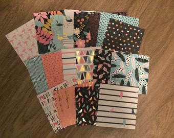 May include: A collection of 15 patterned scrapbook paper squares in various colors, including pink, blue, black, and gold. The patterns include flamingos, birds, geometric shapes, and text.