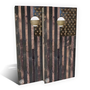 May include: Two wooden cornhole boards with a distressed American flag design. The boards are painted in shades of blue, red, and white, with a distressed wood grain effect. Each board has a circular hole in the center.