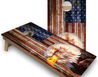 May include: A wooden cornhole game with a distressed American flag design and a bald eagle graphic. The game features a red, white and blue colour scheme.