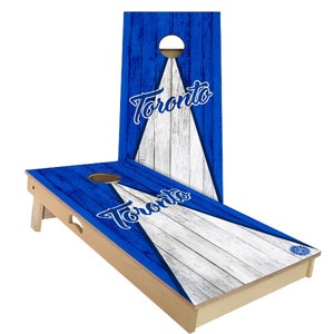 May include: A blue and white wooden cornhole set with the word "Toronto" printed on the boards. The boards have a distressed wood look.