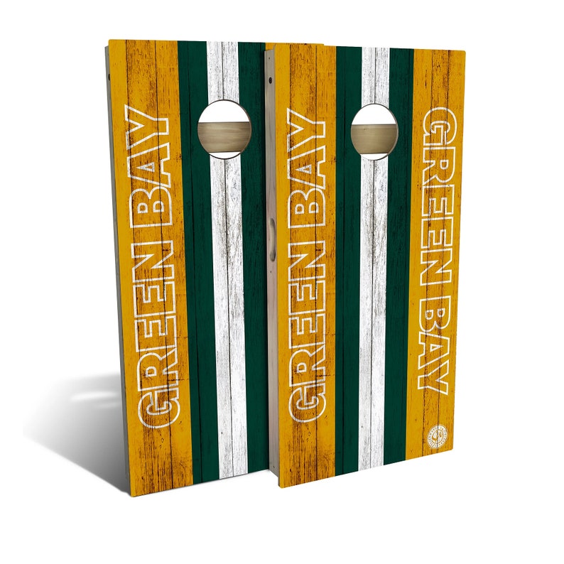 Pu&ograve; includere: Un paio di tavole da cornhole in legno a tema Green Bay Packers. Le tavole sono dipinte con un aspetto legno invecchiato e presentano i colori della squadra: verde, oro e bianco. Le parole "Green Bay" sono scritte in bianco sulle tavole.