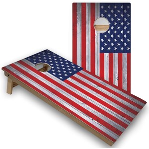 May include: A wooden cornhole game with a distressed American flag design. The boards are painted with red, white, and blue stripes and have a circular hole in the center.