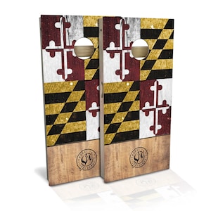 May include: A pair of wooden cornhole boards with a distressed Maryland flag design. The boards are painted in red, yellow, black, and white. Each board has a circular hole in the center and a logo that reads "Tilghman's Cornhole".