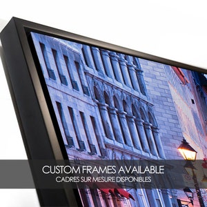 Puede incluir: Una fotograf&iacute;a enmarcada de una escena de calle de la ciudad con edificios, una farola y un toldo rojo. El texto "CUSTOM FRAMES AVAILABLE" y "CADRES SUR MESURE DISPONIBLES" es visible en la parte inferior de la imagen.
