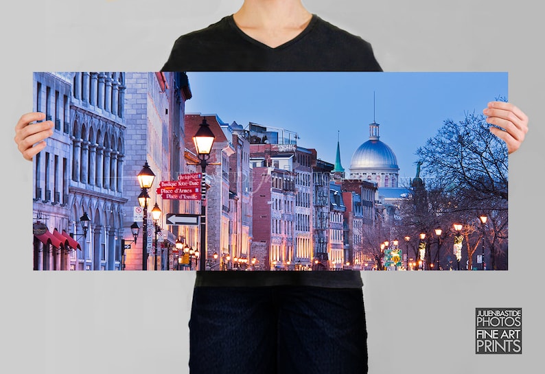Puede incluir: Una vista panor&aacute;mica de una calle en Montreal, Quebec, Canad&aacute; al atardecer. La calle est&aacute; bordeada de edificios hist&oacute;ricos y farolas. La Bas&iacute;lica de Notre-Dame es visible en la distancia.