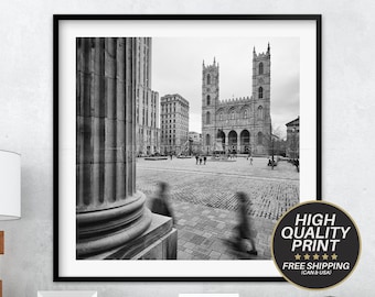 Puede incluir: Fotografía en blanco y negro de una gran iglesia con dos torres altas en el centro de una plaza de la ciudad. La iglesia está rodeada de edificios y algunas personas caminan por la plaza.
