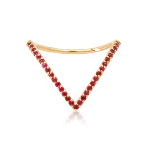 Peut inclure: Une bague en or avec un design en forme de V sertie de petites pierres précieuses rouges.