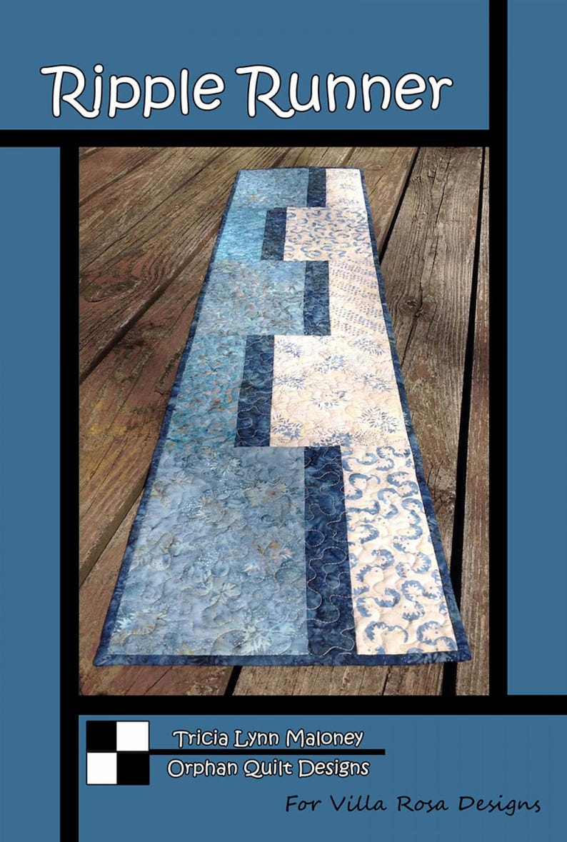 May include: A quilted table runner with a blue and white floral pattern. The runner features a rectangular design with the text "Ripple Runner". The design includes various shades of blue and white.