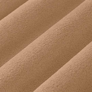 May include: Close-up of a soft, tan fabric with a plush texture. The fabric is folded in diagonal lines, creating a sense of depth and highlighting the material's tactile quality. The color is a warm, neutral tone.
