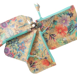 May include: A set of three cork pouches featuring a vibrant floral print with shades of red, blue, purple, and green. Each pouch is equipped with a bright turquoise zipper closure and a matching turquoise zipper pull, showcasing a natural cork texture.