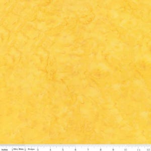 May include: A close-up of a yellow fabric with a mottled pattern. The fabric has a textured appearance with variations in color, ranging from light to medium yellow. The image includes a ruler at the bottom, with measurements in inches.