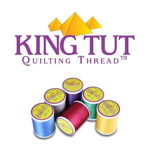 May include: Image features spools of King Tut quilting thread in various colors, including blue, red, purple, green, and yellow. The brand name and logo, featuring pyramids, are displayed above the spools. Each spool is labeled with the brand name and thread weight.