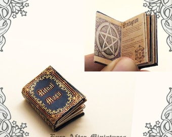 May include: A miniature book titled "Ritual Magic" with a blue cover and gold accents. The book is open to a page with a pentagram and the word "Pentagram" written in gold lettering.