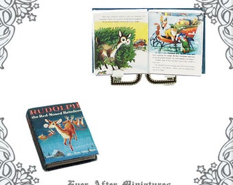May include: A miniature book titled "Rudolph the Red-Nosed Reindeer" with a red and blue cover and a picture of Rudolph on the front. The book is open to a page with a picture of Rudolph in a forest. The book is next to a miniature open book with a blue cover and a picture of Santa Claus on a sleigh.